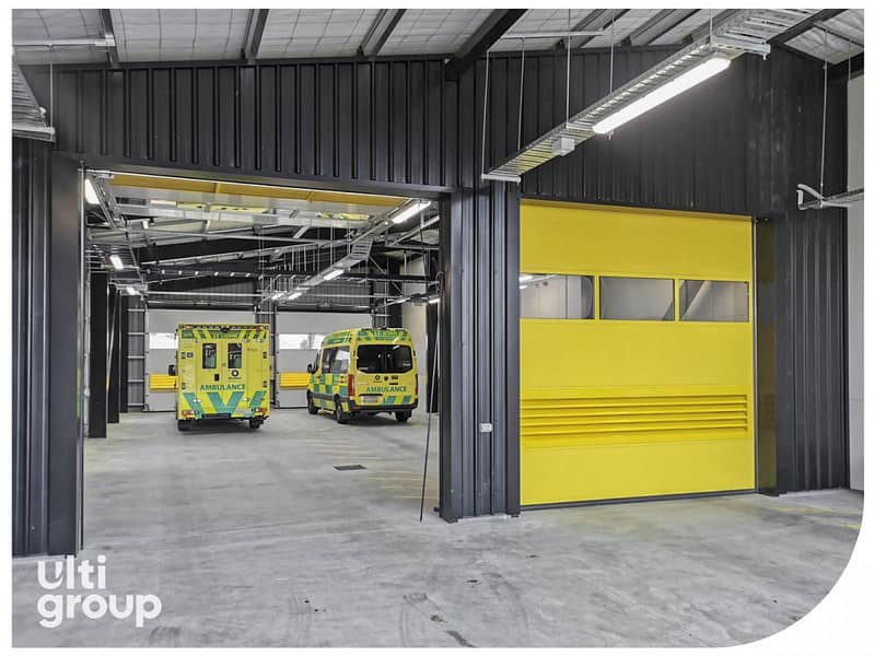 Yellow sectional industrial doors installed in an ambulance station.
